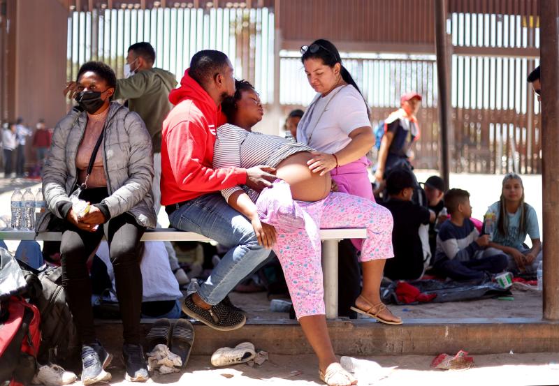Eine schwangere Einwanderin aus Haiti wird von ihrem Partner und einer anderen Einwanderin unterstützt, während sie Wehen hat, nachdem sie am 21. Mai 2022 in San Luis, Arizona, aus Mexiko mit der Grenzbarriere zwischen den USA und Mexiko im Hintergrund überquert wurde. (Foto: AFP) Eine schwangere Einwanderin aus Haiti wird von ihrem Partner und einer anderen Einwanderin unterstützt, während sie Wehen hat, nachdem sie am 21. Mai 2022 in San Luis, Arizona, aus Mexiko mit der Grenzbarriere zwischen den USA und Mexiko im Hintergrund überquert wurde. (Foto: AFP)