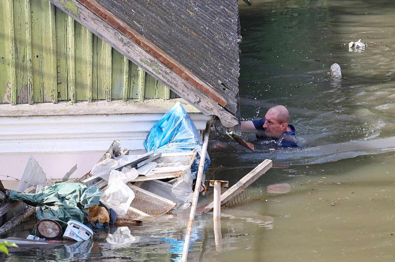 Ein Anwohner schwimmt am Mittwoch an einem Haus in einem überschwemmten Gebiet von Cherson vorbei, nachdem der Kakhovka-Staudamm in der Nähe der Stadt im Süden der Ukraine zerstört wurde. (Foto: AFP)