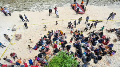 An einem indonesischen Strand zusammengekauert flehen gestrandete Rohingya um Gnade