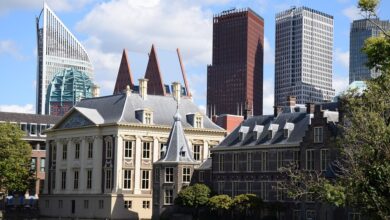 Die beiden schütteln vor den Fahnen inrer Länder die Hände und schauen nach vorne.